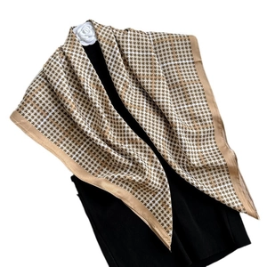 Elegant beige and brown houndstooth silk scarf worn as a shawl on a mannequin