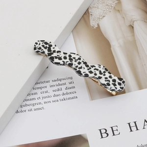 Minimalist wave-shaped acetate hair clip with classic black and white cow pattern