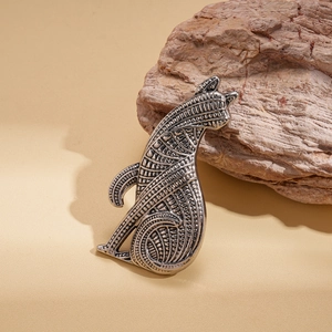 Macro detail of vintage silver dog brooch showing intricate geometric engraved patterns