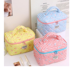 Close-up of quilted plaid cosmetic bags with bow prints and double zipper handles