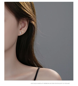 Close-up of star-shaped S925 silver studs with blue zircon on a model's ear lobe