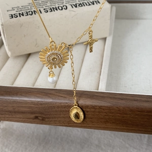 Detail of 925 silver necklace with sun pendant, white pearl charm, and gold cross