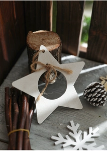 Macro shot of a rustic white wooden star ornament with a bell and pine cones backdrop