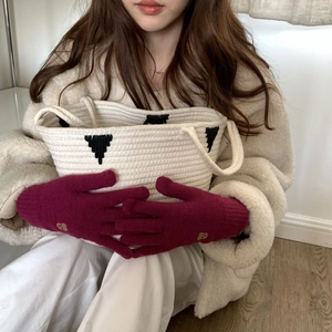 Detail of red knitted fingerless gloves with bear embroidery and white knit handbag