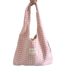 Pink and white checkered tote bag with woven shoulder strap and brand label on white background