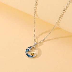Detailed close-up of a blue sea wave and sun enamel pendant on a silver necklace
