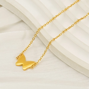 Detailed view of a golden butterfly pendant on a fine link chain against white silk