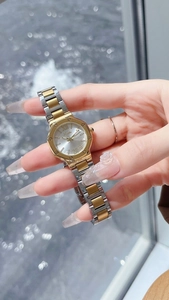 Montre femme bicolore élégante avec lunette octogonale dorée sur fond d'eau scintillante