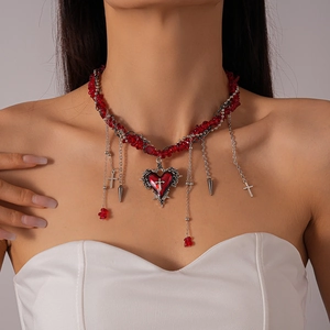 Gothic choker detail with red beads, silver chains, and thorny heart cross pendant