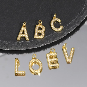 Macro shot of gold-plated letter pendants with sparkling cubic zirconia on stone base