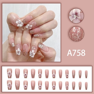 Macro detail of nude pink gradient press-on nails with white floral art and silver glitters