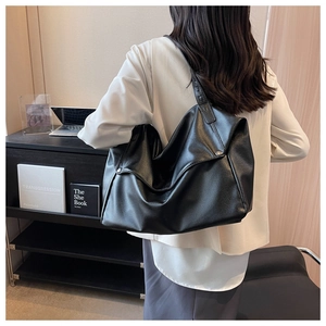 Detail of black large capacity hobo tote bag with lychee texture in a minimal office setting