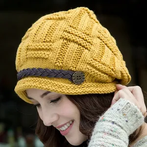 Close-up of yellow knit beanie with woven leather strap and retro metal button detail