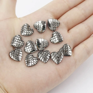 Macro shot of 12 heart-shaped fish scale resin charms held in a palm for DIY crafts