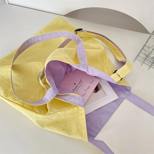 Detail of a yellow canvas tote bag with lilac interior lining and adjustable buckle