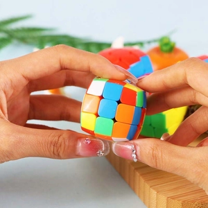 Miniature smooth 3x3 speed cube keychain in vibrant colors held in hands for play