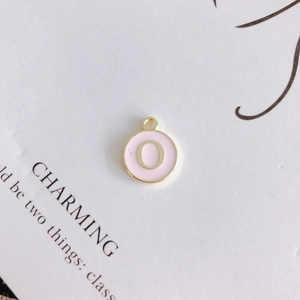 Detail of pink enamel round charm with golden letter O and metallic ring for DIY jewelry