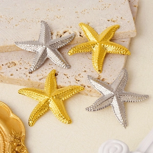 Macro view of gold and silver starfish pendants with textured finish on stone surface