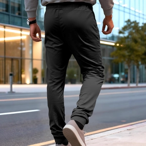 Men's black athletic joggers with elastic waist and cuffs, shown in an urban street setting