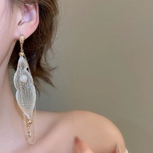 Close-up of golden mesh leaf earrings with pearl and long tassel fringe on model