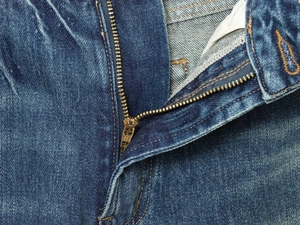 Detail of high-quality bronze metal zipper and blue denim texture on casual jeans