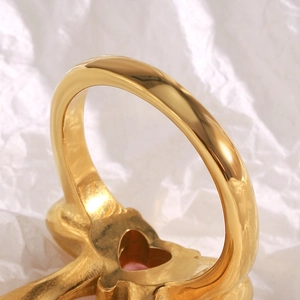 Macro detail of 18K gold plated ring featuring heart-shaped cutout and pink gemstone back