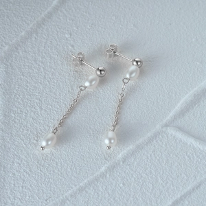 Macro shot of S925 silver long tassel earrings with lustrous white pearls and chain details