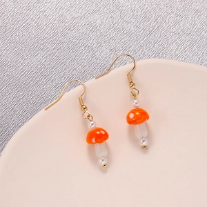 Gros plan de boucles d'oreilles champignons en céramique orange avec pois et perles