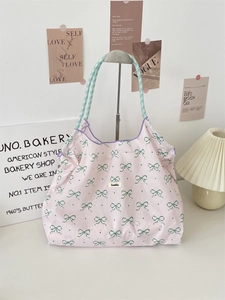 Pink tote bag with green bow print and purple checkered straps in a stylish lifestyle setting