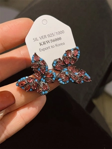 Macro shot of S925 silver butterfly earrings with red zirconia and blue turquoise beads