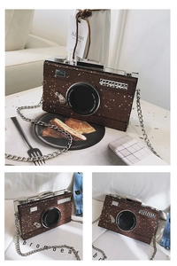Detail of glitter camera-shaped crossbody bag with gold stars and silver metal chain