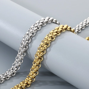 Close-up of gold and silver stainless steel woven hip-hop chains on a gray stand