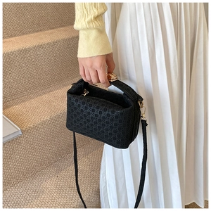 Detailed view of woven black handbag texture with gold hardware on beige carpet
