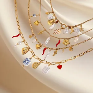 Golden stainless steel heart and pearl charm necklace displayed on beige silk background