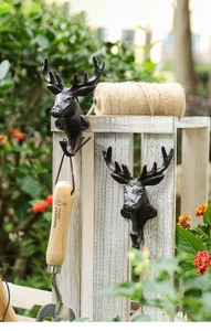 Detail of vintage cast iron deer head hook mounted on rustic white wood in garden