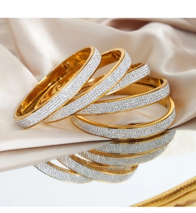 Detailed macro shot of a gold crystal-paved bangle on luxurious champagne silk fabric