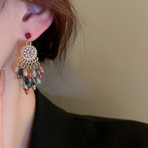 Close-up of vintage tassel earrings with red gemstones and colorful crystal beads