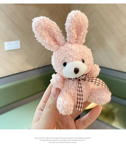 Close-up of pink plush bunny keychain with lamb wool texture and brown plaid bowtie