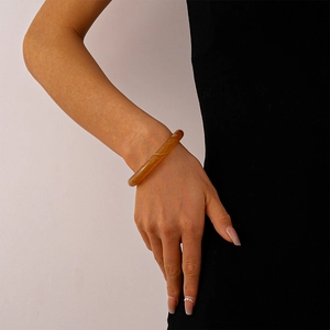 Detail view of a vintage amber acrylic cuff bracelet with marble texture worn on wrist