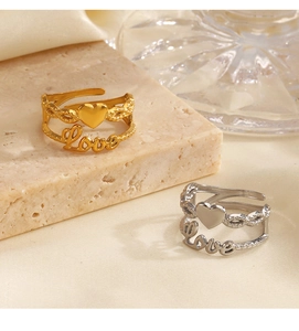 Detail view of gold and silver double-layered heart and Love rings on silk fabric