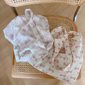 Sacs cabas en coton avec imprimés nœuds roses et violets sur une chaise en rotin