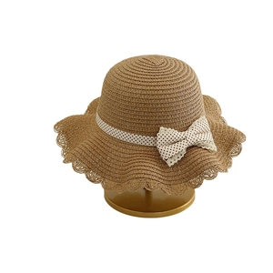 Kids woven straw sun hat with white polka dot bow on a golden display stand