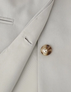 Detailed macro view of light grey twill fabric with marble texture resin button on blazer