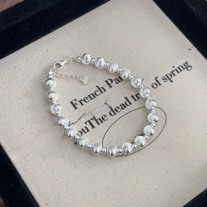 Detailed macro view of S925 sterling silver beaded bracelet with heart charm and lobster clasp