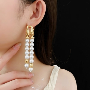 Detail of vintage gold layered tassel earrings with white pearls worn by a model