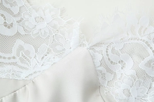 Detail view of white eyelash lace and satin fabric texture on a women dress