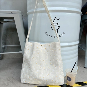 Close-up of small yellow daisy patterns on canvas bag with a snap metal button closure