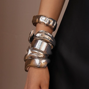Detail view of silver acrylic bangles with liquid texture and geometric folds on model arm