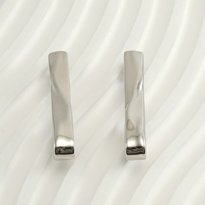 Macro shot of silver twisted wave earrings with polished stainless steel texture
