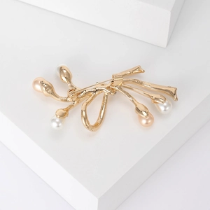 Élégante broche corail dorée avec perles blanches et roses sur un support blanc moderne